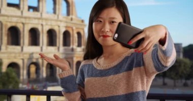 Gündelik milenyum kadını, İtalya 'daki Roma Kolezyumu önünde selfie çekmek için akıllı telefon kullanıyor. Antik Avrupa şehrinde cep telefonu kamerasıyla selfie çeken mutlu Asyalı genç kadınların yakın çekimi. 4k