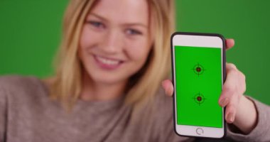 Yeşil ekranda Chroma anahtarıyla cep telefonunu gösteren sevimli genç bir kadının portresi. Anahtar ya da birleşik olmak üzere yeşil ekranda.
