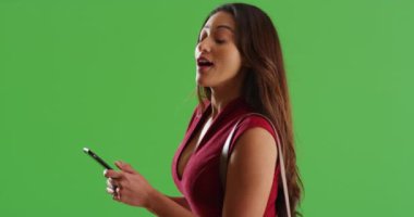 Çekici Latin kadın, etrafına bakıyor ve yeşil ekranda akıllı telefondan mesajlaşıyor. Anahtar ya da birleşik olmak üzere yeşil ekranda.