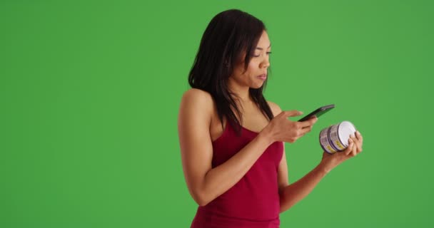 非洲裔美国妇女使用智能手机饮食跟踪应用程序检查绿色屏幕上的食物营养 黑色千年女性 手机在绿色屏幕上拍摄罐装食品的照片 — 图库视频影像