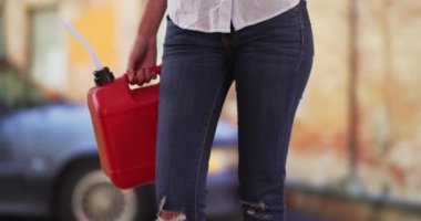 Arabanın benzini bittikten sonra yakıta ihtiyacı olan bir kadının kırmızı benzin bidonuna yakın çekim. Benzin bidonlu kadın belinin dar bir görüntüsü caddede arabada bekliyor. 4k