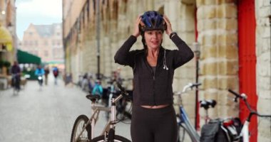 Dişi bisikletçi dışarıda akıllı kasetini kullanıyor. Bisikletiyle gülümseyen sportif kadın portresi. 4k