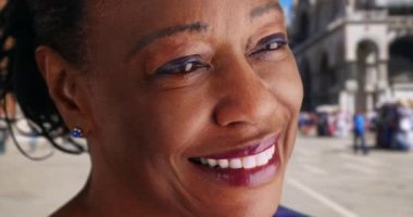 St. Mark Meydanı 'ndaki yaşlı siyahi kadının uzaktan gülümsemesini yakından çek. Afro-Amerikalı kadın turist Venedik 'te eğleniyor, gülümsüyor ve gülüyor. 4k