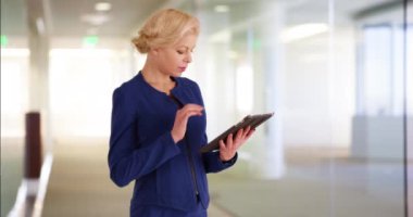 İş yerinde dokunmatik ekranı kullanan başarılı bir iş kadınının portresi. Profesyonel Kafkas çalışanı ofis koridorunda çalışmak için modern tablet kullanıyor. 4k