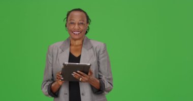 Siyah bir iş kadını yeşil ekranda tabletini kullanırken gülüyor. Anahtar ya da birleşik olmak üzere yeşil ekranda.