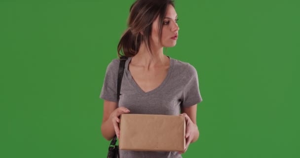 女性は緑の画面で画面を歩く前に小包の上のアドレスを読んでいます 百万人の白人の少女が郵便局に向かう前に彼女の出荷をチェックしてる キーや合成のための緑の4K — ストック動画