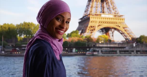 フランスの美しい若いイスラム教徒の女性の肖像幸せと興奮 スカーフでアフリカの女性を笑顔エッフェル塔とセーヌ川を観光 — ストック動画