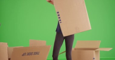 Genç bayan, yeşil ekrandaki kameranın önünden ağır karton kutu taşıyor. Anahtar ya da birleşik olmak üzere yeşil ekranda.