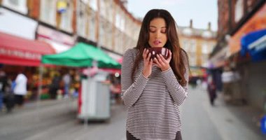 Brixton Caddesi 'ndeki marketten alışveriş yapan güzel Latin bir kadın. Dışarıda seramik kaseye bakan çekici genç bir kadının portresi. 4k