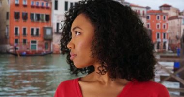 İtalya Venedik 'teyken, kasvetli bakışlı siyah bir kadın kameradan yüzünü çeviriyor. Venedik 'teki Grand Canal' ın perdesinden bakan düşünceli Afro-Amerikan kadın. 4k