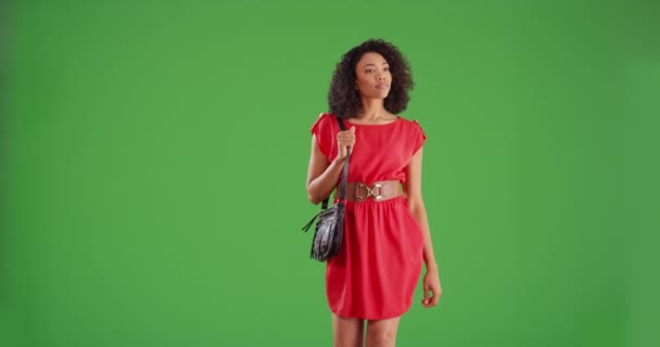 身穿红色衣服 头戴钱包的时髦黑人妇女在绿色屏幕的背景下走向摄像机 时尚的非洲裔美国女人一边走一边笑着为绿屏作曲 — 图库视频影像