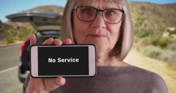 一个长相忧郁的老妇人在沙漠路上停了下来 没有电话服务 白色女性手持电话 手机显示屏上没有服务警告闪闪 — 图库视频影像