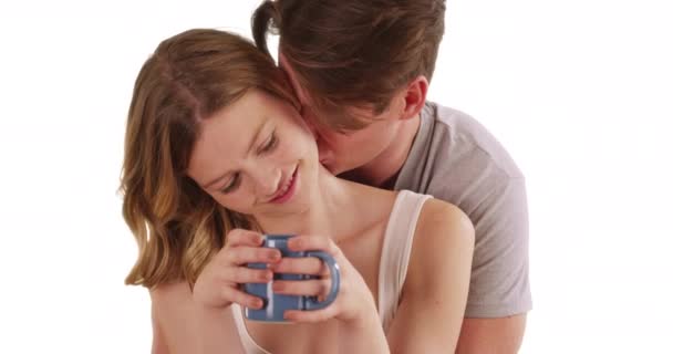 迷人的白人男性拥抱女友咖啡杯从后面 微笑和笑在工作室 幸福的年轻夫妇穿着随意拥抱在白色背景上的画像 — 图库视频影像