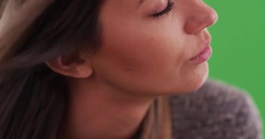 20 'li yaşlarında genç ve güzel bir bayanın yüzüne saçlarını süzülen rüzgar aşırı yakın plan. Gözleri kapalı bir kız. Tuşlama veya birleştirme için yeşil üzerine 4K