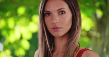 Esmerin yakın plan portresi. Rüzgâr saçlarını gür doğa ortamında dalgalandırıyor. 20 'li yaşlarda güzel beyaz bir kız. Uzun kahverengi saçlı, yeşil doğal bir çevrede. 4k