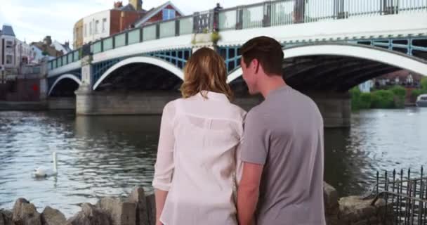 温莎的年轻夫妇在河岸观看天鹅的后视镜 丈夫和妻子在泰晤士河边的户外享受着悠闲的一天 — 图库视频影像