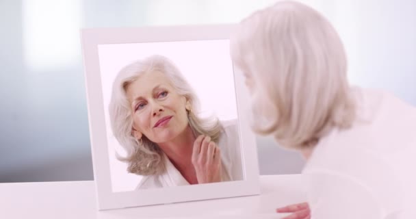 漂亮成熟的女人在50多岁的时候检查她在浴室里镜子里的倒影 漂亮的老年妇女正对着镜子里的倒影笑着 — 图库视频影像