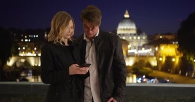 Beyaz bir kadın ve erkek arkadaşı akıllı telefondan mesajlaşıyorlar. Milenyum çifti Roma 'da geceleri cep telefonu kullanıyor. 4k