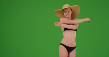 Yeşil ekranda dönen ve gülümseyen güneş şapkası takan güzel bir milenyum kadını. Anahtar ya da birleşik olmak üzere yeşil ekranda.
