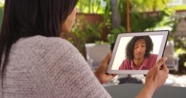 Siyah kadının tabletli erkek arkadaşıyla görüntülü konuşma sahnesinin üstünden. İki arkadaş görüntülü görüşme yoluyla konuşmaktan zevk alıyor. 4k