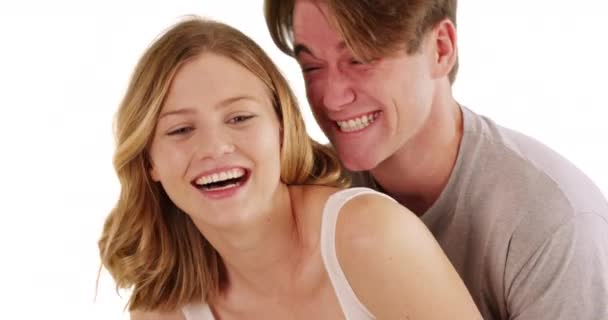在白人背景下 男人从后面紧紧拥抱着笑着的女朋友 一对年轻夫妇穿着随意拥抱在演播室里的肖像 — 图库视频影像