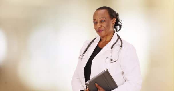一位年长的黑人医生在她的办公室摆出一副画像的姿势 一位年迈的非裔美国人站在她的办公室里 她的平板电脑 — 图库视频影像