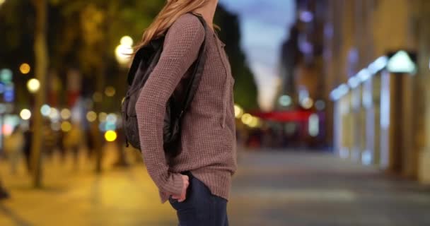 年轻的白人女人晚上背着背包20多岁的女性晚上站在城市街道上 — 图库视频影像