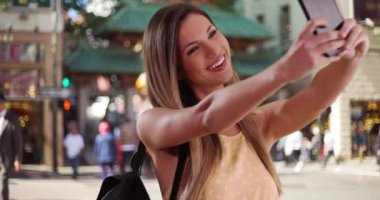 Mutlu milenyum kızları San Francisco caddesinde akıllı telefonlarıyla selfie çekiyor. 20 'li yaşlardaki bir kadın San Francisco Çin Mahallesi' nde telefonla kendi fotoğrafını çekiyor. 4k