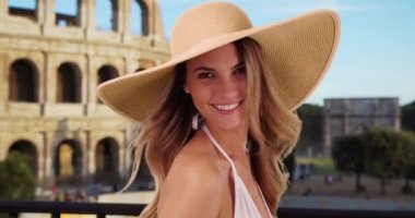 Roma 'da güneş şapkası takan gülümseyen bir turist kadın. Kolezyum yakınlarında kameraya gülümseyen güzel beyaz bir kızın portresi. 4k
