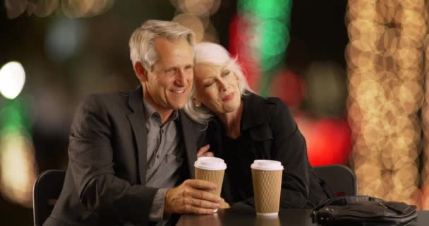 先輩夫婦がコーヒーを飲みながらカフェの前に座っています シニアカップルは一緒にコーヒーを楽しんでいます — ストック動画