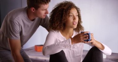 Birlikte yemek odası pencereden dışarı bakarak oturan genç çok ırklı çift