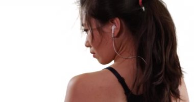 Asyalı milenyum koşucusunun beyaz arka planda izole edilmiş kulaklıklarıyla dinlendiği yakın plan. Kopya alanı için kasvetli ifadesi olan genç bayan koşucunun profili. 4k