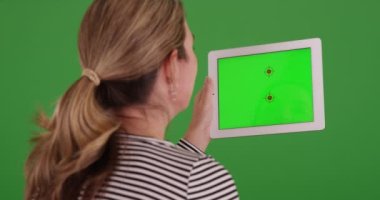 Yeşil ekranda tablet kullanan aile üyelerini ya da aileleri arayan kadın videosu. Anahtar ya da birleşik olmak üzere yeşil ekranda.