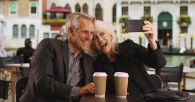 Venedik 'te selfie çeken olgun bir çift. Kafkas erkek ve kadın portresi tatillerinde fotoğraf çekiyor. 4k