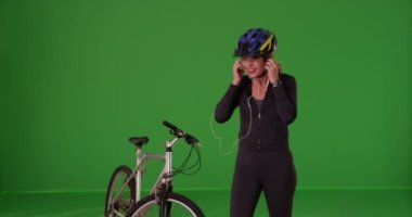 Atletik giyimli beyaz bir kadın yeşil ekranda egzersiz sonrası cihaz kullanıyor. Anahtar ya da birleşik olmak üzere yeşil ekranda.