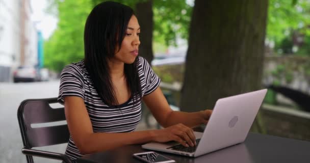 外のノートパソコンで働く黒人女性とコーヒーを飲む アフリカ系アメリカ人女性で 上司にコーヒーメールを書いている — ストック動画