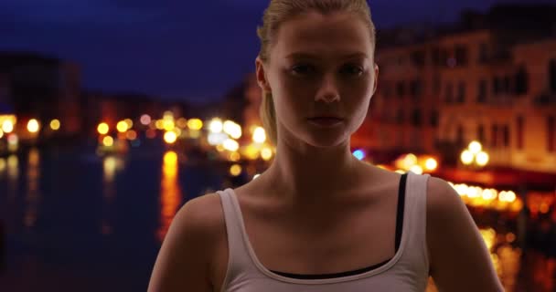 威尼斯美丽而性感的金发女人回头看 白种人女人在大运河边的夜晚 看着镜头充满自信 — 图库视频影像