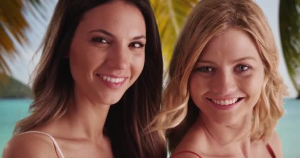 一对笑容可亲的年轻女士在热带海滩上快乐地摆姿势 两名漂亮的高加索女性在海滩边的相机前微笑着度假 — 图库视频影像