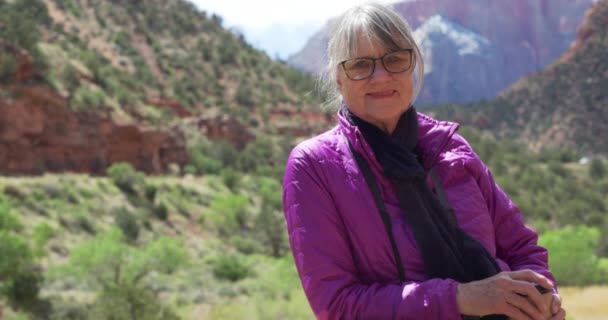 在犹他州的砂岩峡谷里 一个健康的老年女子在户外微笑的美丽画像 近距离观看迷人的老年女性享受大自然的美景 并对着相机微笑 — 图库视频影像