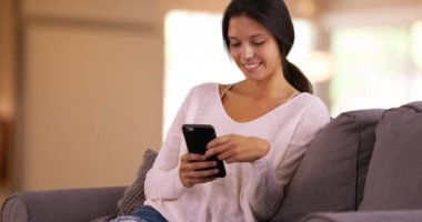 Genç beyaz kadın interneti gezmek için cep telefonunu kullanıyor. Millennial beyaz kız oturma odasında akıllı telefonunu kullanıyor. 4k