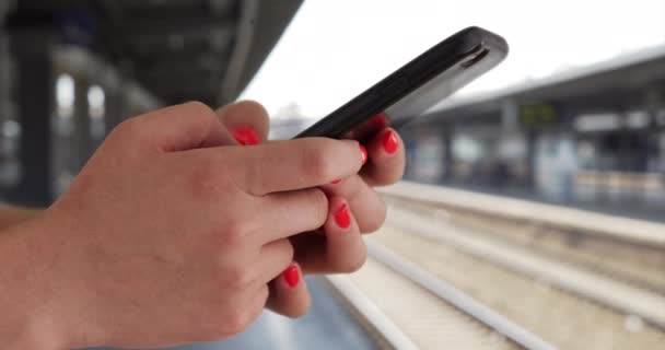 地下鉄のプラットフォーム上のスマートフォンで若い女性のテキストメッセージのプロフィールを閉じます 電車の駅でテキストを送信するためにモバイルデバイスを使用して100万人の女性のタイトなショット — ストック動画