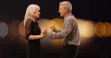 Tatlı yaşlı çift birlikte dans ediyor. Arka planda dans eden yaşlı çift. 4k