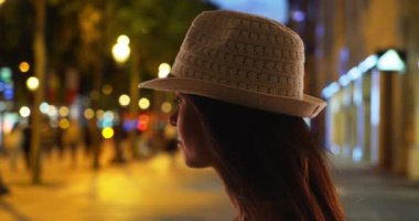 Champs-Elysees 'de fötr şapkalı genç bir kadının silueti. Gece Paris caddesinde yüzü kasvetli esmer bir kadının yan görüntüsü..