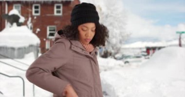 Güzel Afro-Amerikalı kadın dışarıda karda cep telefonundan mesaj atmak için eldivenlerini çıkarıyor. Kışlık ceketli, açık hava ortamında cep telefonuyla mesajlaşan sevimli siyahi kadın. 4k