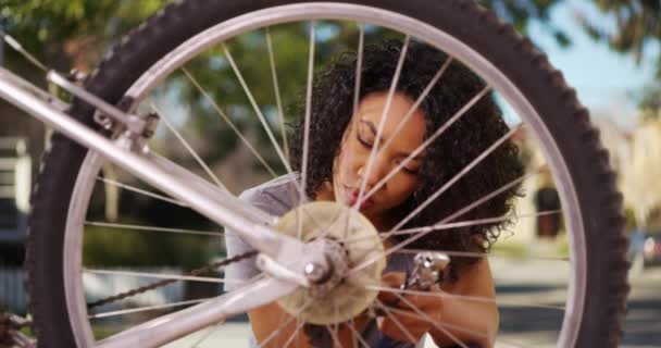 郊外のスマートブラック女性の自転車ホイールを固定します 屋外設定で自転車を専門的に修理サイクリストの肖像画 — ストック動画