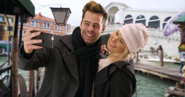 ヴェネツィアの魅力的な観光のカップルは 自撮りを取ります 白人男性と女性がリアルト橋で笑顔で一緒に写真を撮る — ストック動画