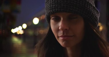 Geceleyin kaldırımda duran bin yıllık bir kadının dramatik yakın plan portresi. 20 'li yaşlarda beyaz bir kızın Kaliforniya' da tatil yaparken kameraya baktığı fotoğraf. 4k