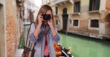 Venedik 'te seyahat fotoğrafçısı dışarıda gülümserken fotoğraf çekiyor. Venedikli kadın turist kamera dışında bir şey çekiyor. 4k