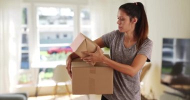 Güzel beyaz kadın evde kargo kutuları taşıyor. Teslimat için elinde paketler olan sıradan esmer kadın. 4k