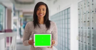 Postanede elinde özel içerik için boş ekranlı tablet tutan çekici zenci kadın portresi. Neşeli postacı yeşil ekranlı bilgisayarı gösteriyor. 4k